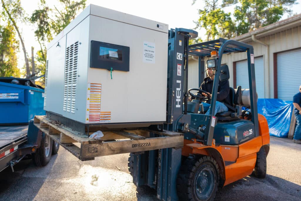 Holly Electric crew moving a whole-home standby generator on a forklift at the Lake City shop